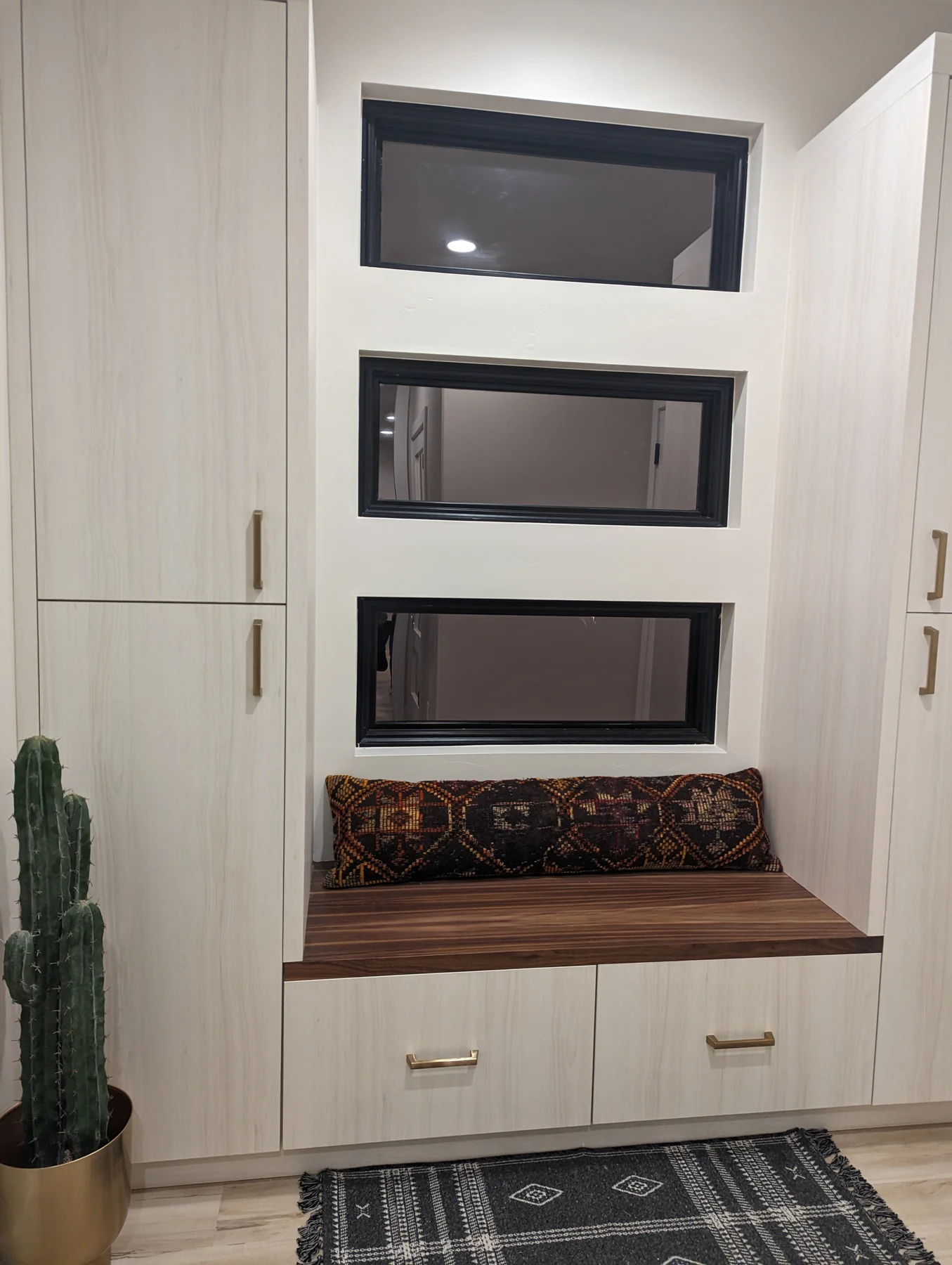 Mudroom with a tall white cabinet, a wood bench seat and drawers beneath a window.