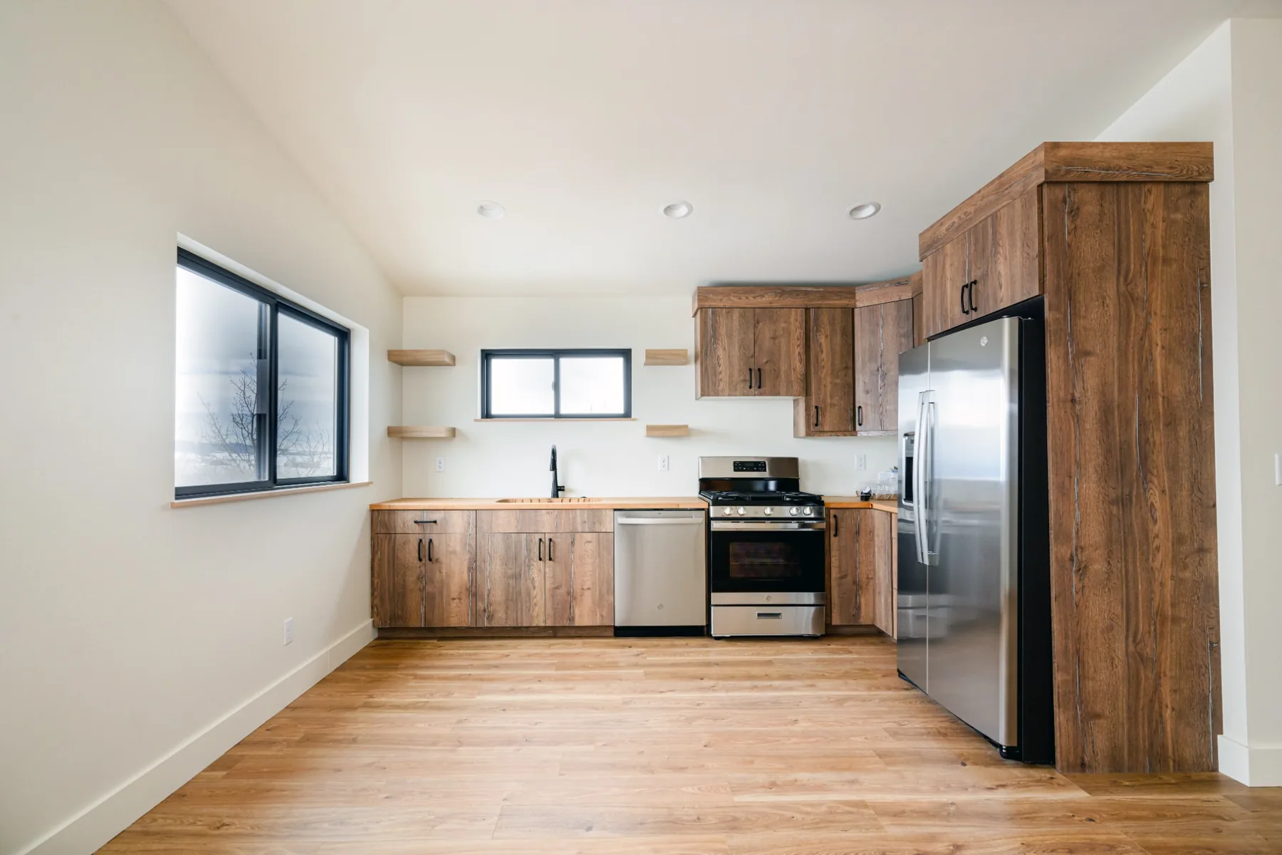 Warm wood cabinetry in a bright room with black-framed windows.